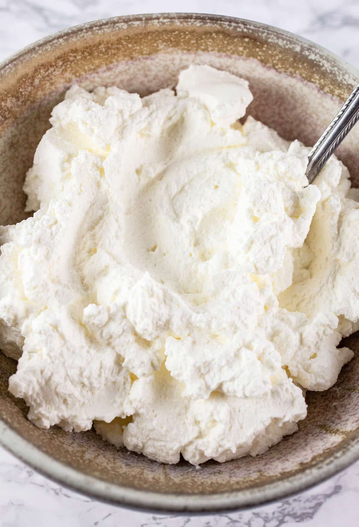 Homemade whipped cream in ceramic bowl.