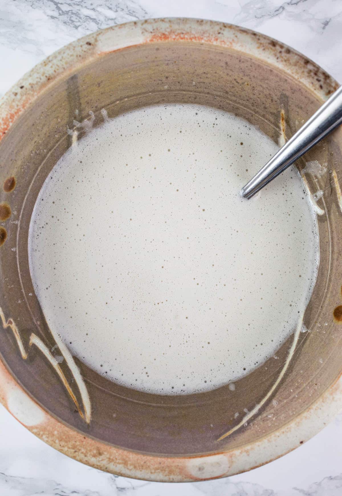 Wet almond cake ingredients combined in ceramic bowl.