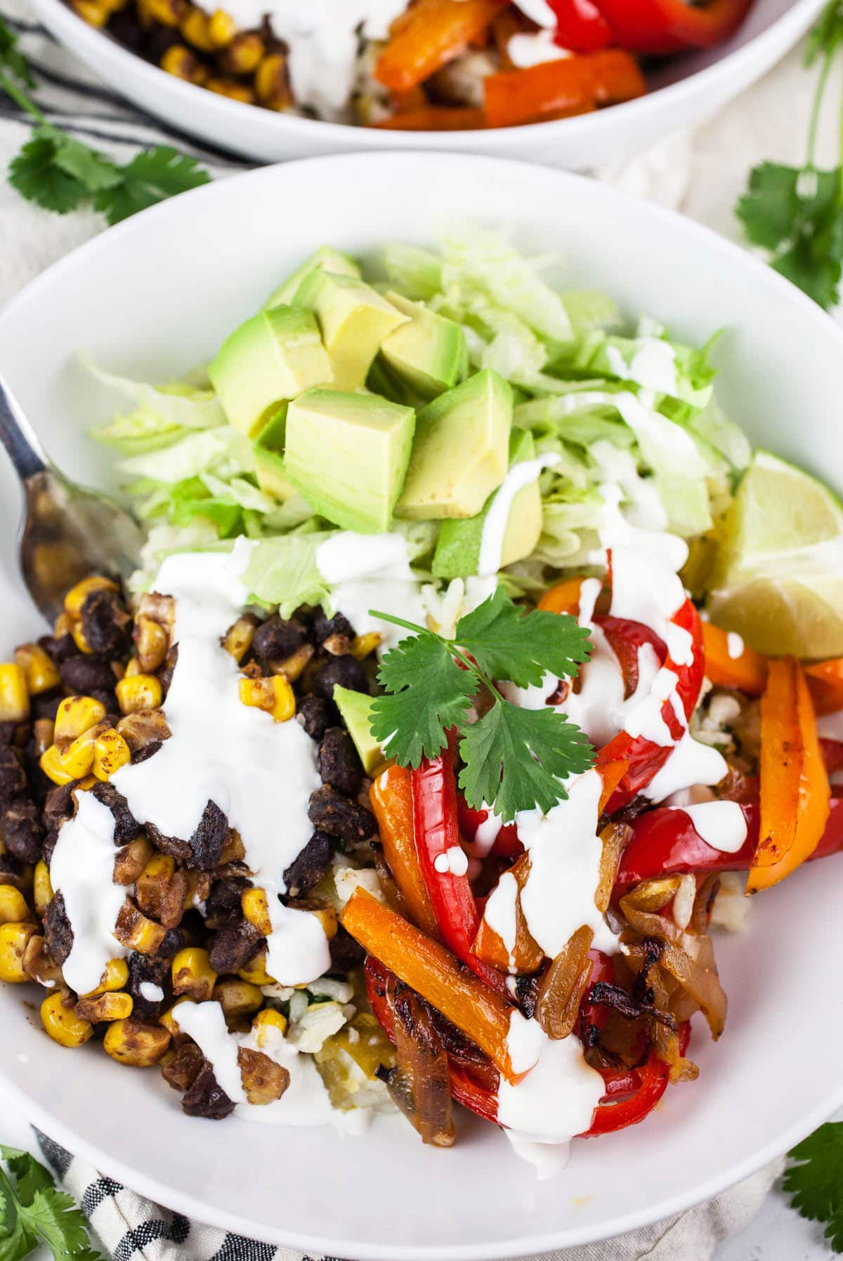 Vegetarian fajita bowl with bell peppers, onions, black beans, corn, avocado, and lime crema.
