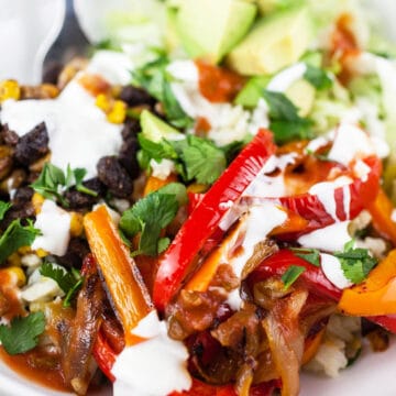 Vegetarian fajita bowls with bell peppers, black beans, corn, avocado, sour cream, and salsa.