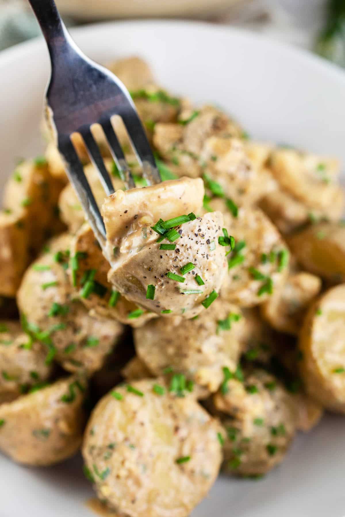 Forkful of chipotle potato salad lifted from white bowl.