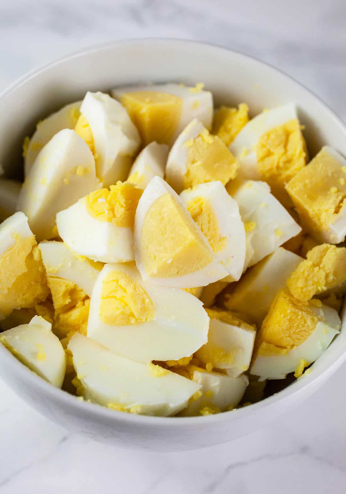 Chopped hard boiled eggs in small white bowl.