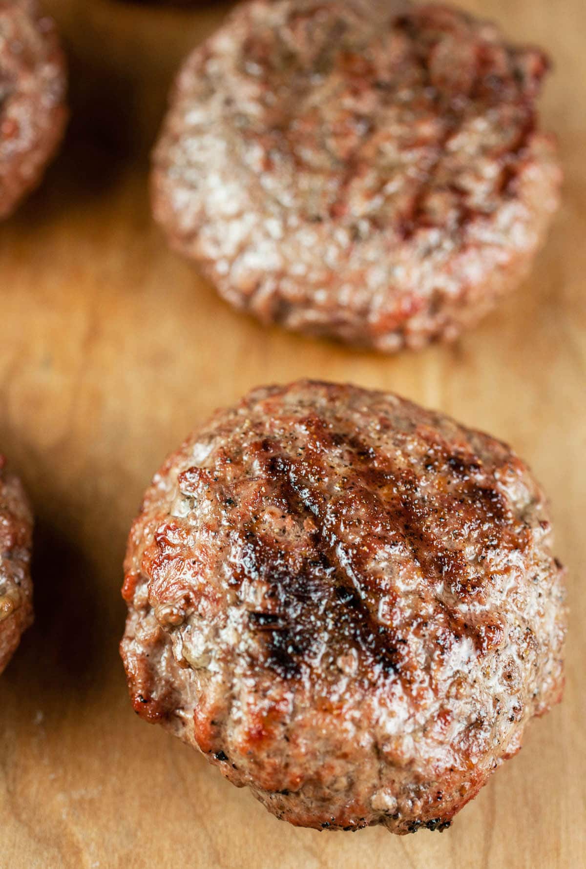 Grilled beef burgers on wooden surface.