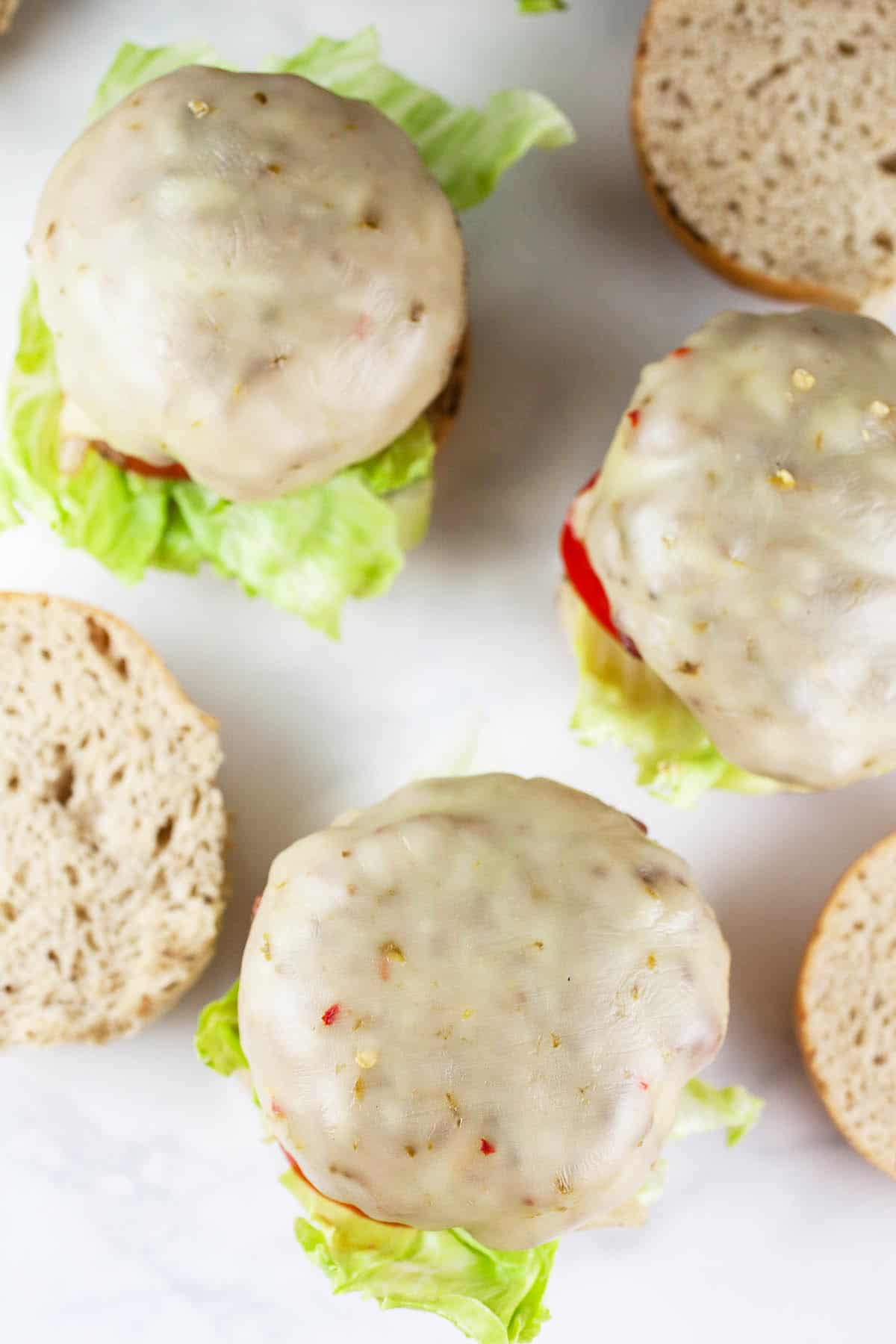 Open faced burgers with melted cheese on buns.