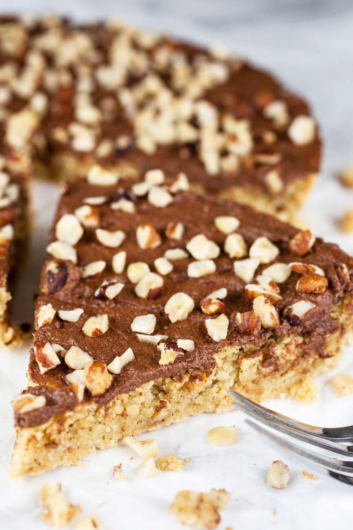 This Italian Chocolate Hazelnut Cake recipe is the best simple and authentic dessert! It's easy to make and full of traditional Italian flavors like coffee, chocolate, and hazelnut. This moist cake is flavored with Frangelico liqueur and topped with a homemade chocolate ganache. Learn how to make this cake from scratch. It's one of my favorite sweet treats and perfect with some espresso! #italian #chocolate #hazelnut #cake #desserts #recipes Slice of Italian chocolate hazelnut cake with fork.