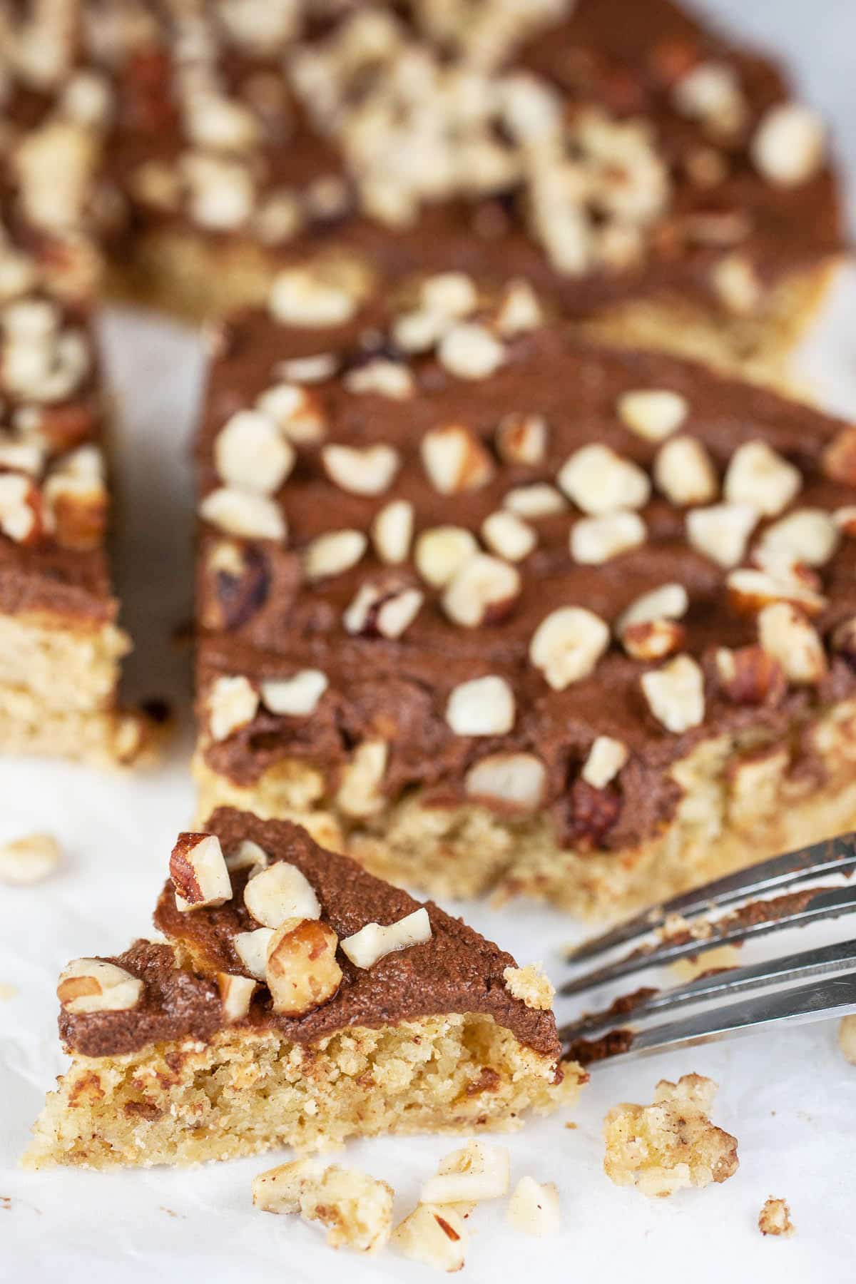 Slice of chocolate hazelnut cake cut with fork.