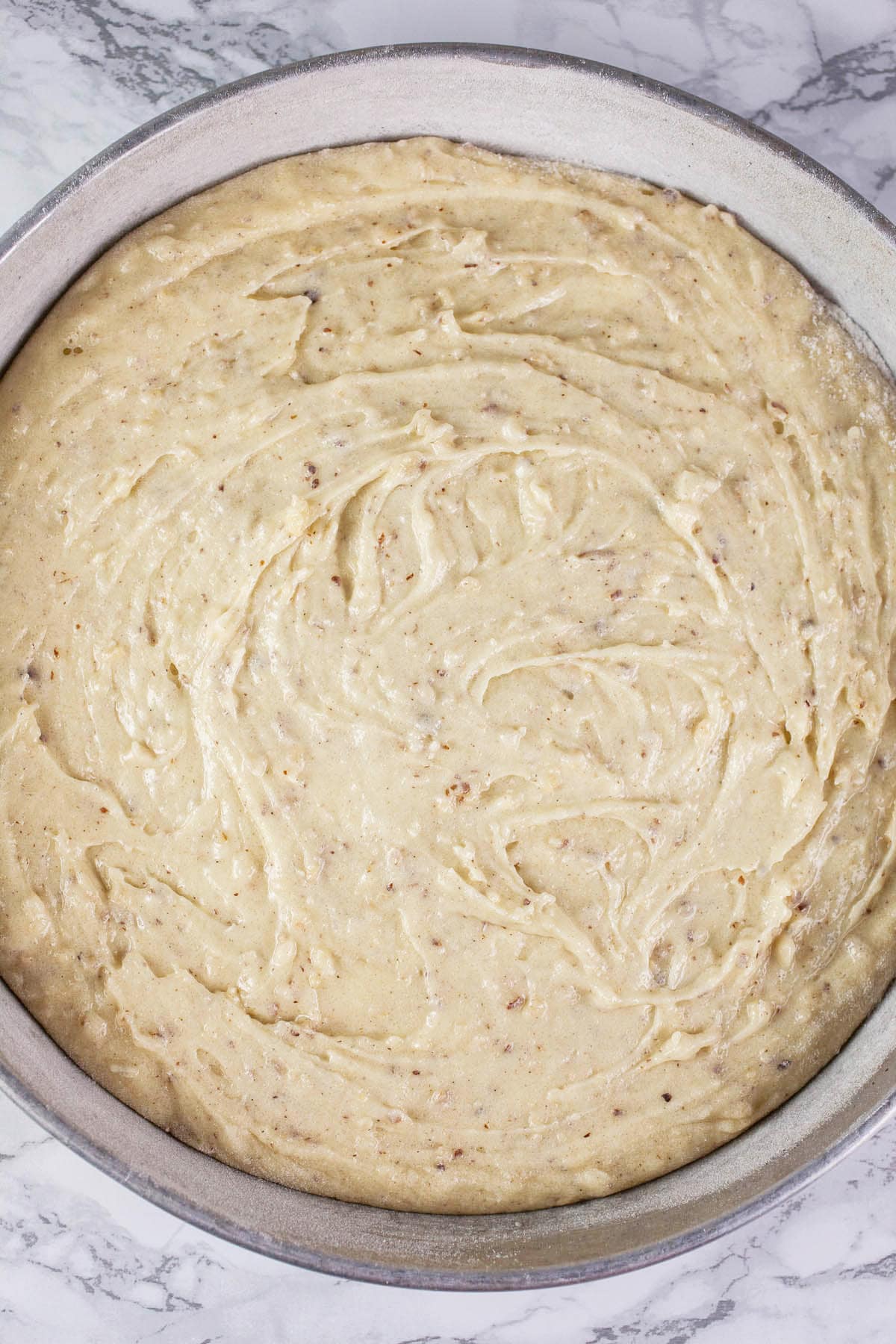 Hazelnut cake batter in round metal cake pan.