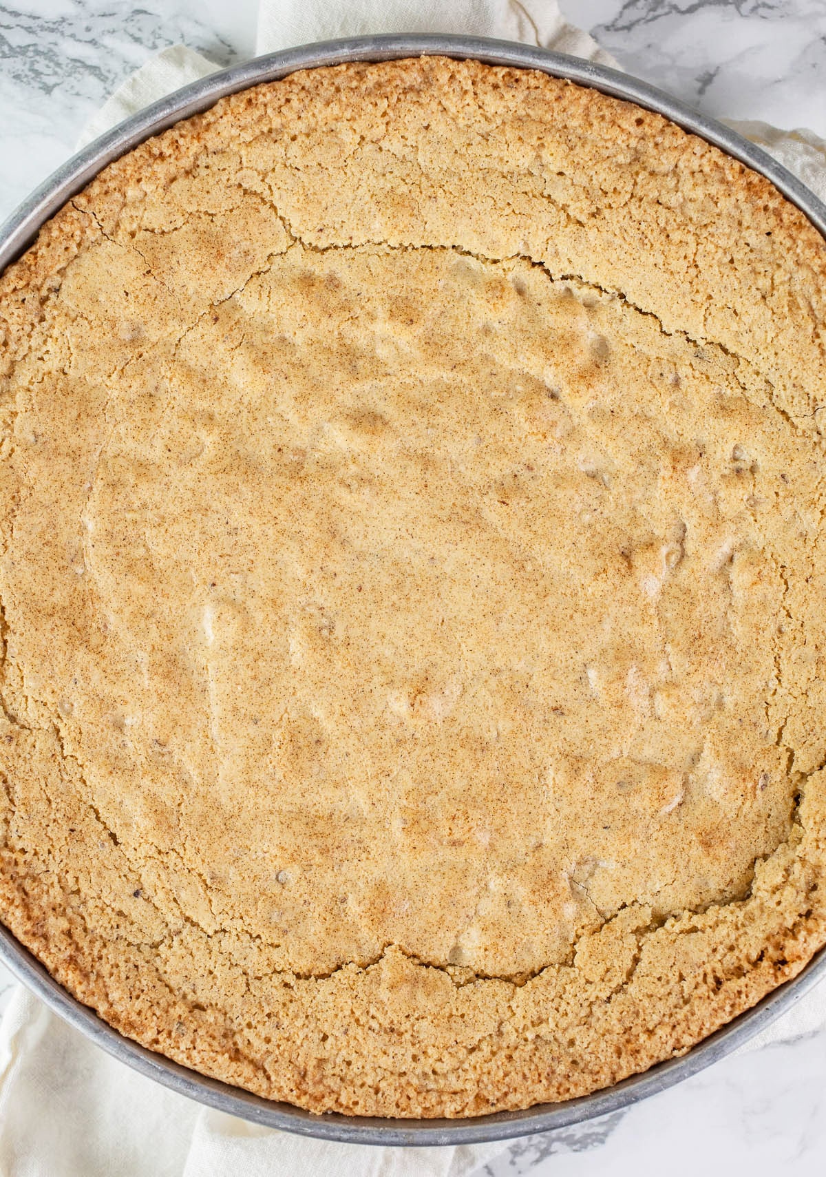 Baked hazelnut cake in round metal cake pan.