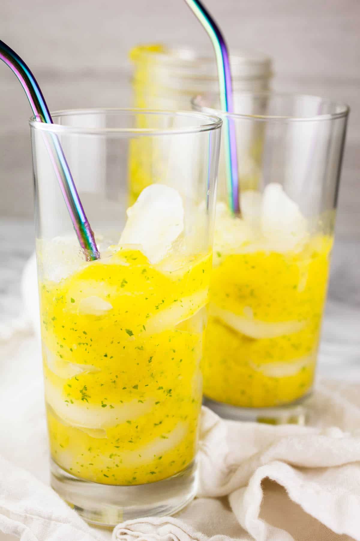 Mango puree in tall glasses with ice cubes and straws.
