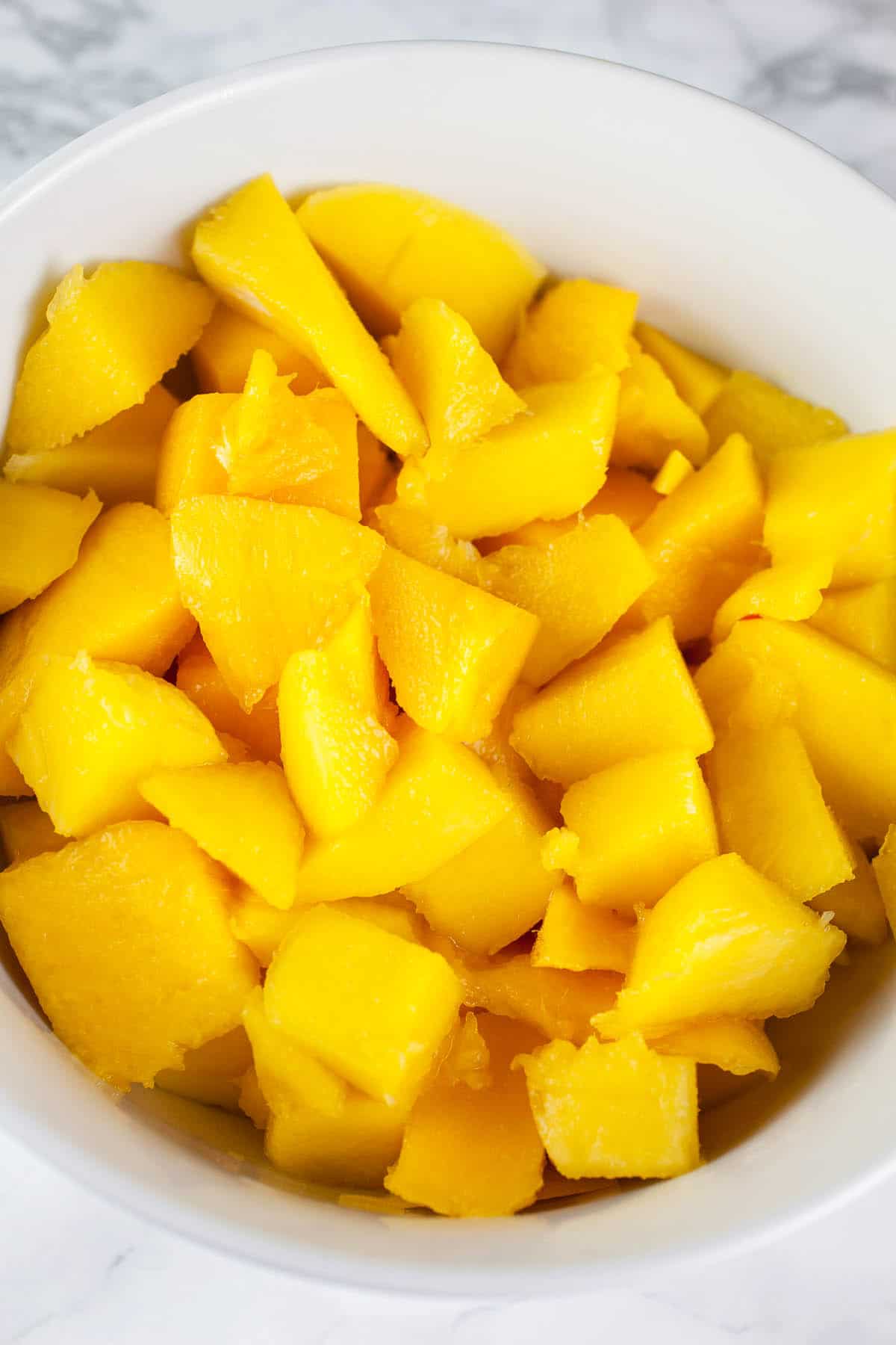 Chopped fresh mango in white bowl.