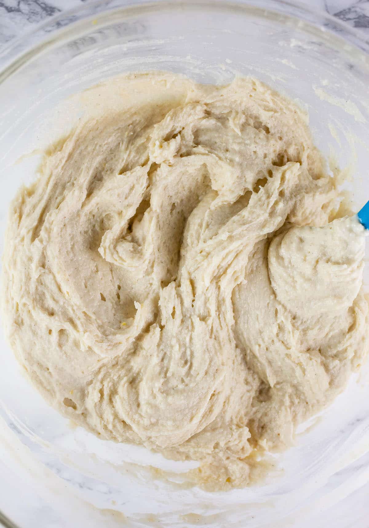 Wet and dry ingredients combined in large glass mixing bowl.