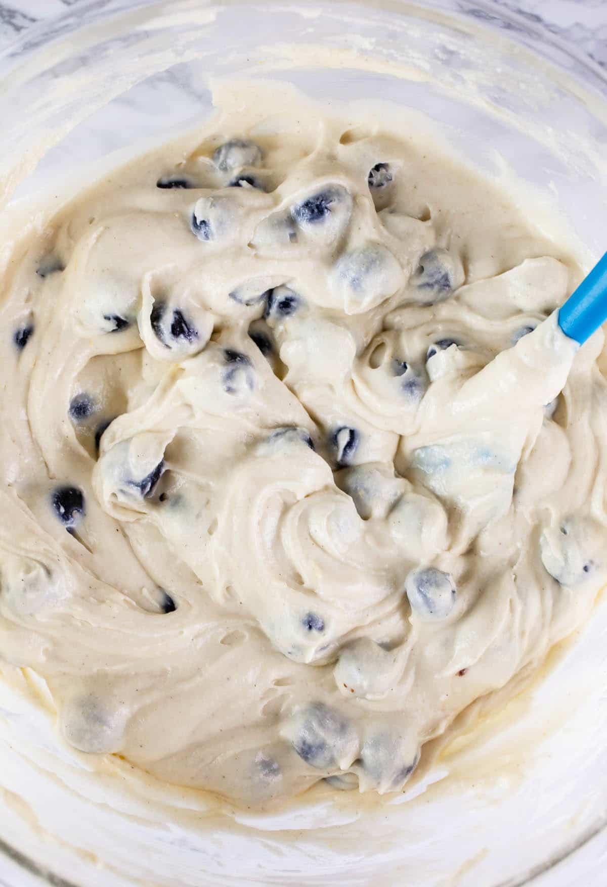 Cake batter combined with blueberries in large glass mixing bowl.