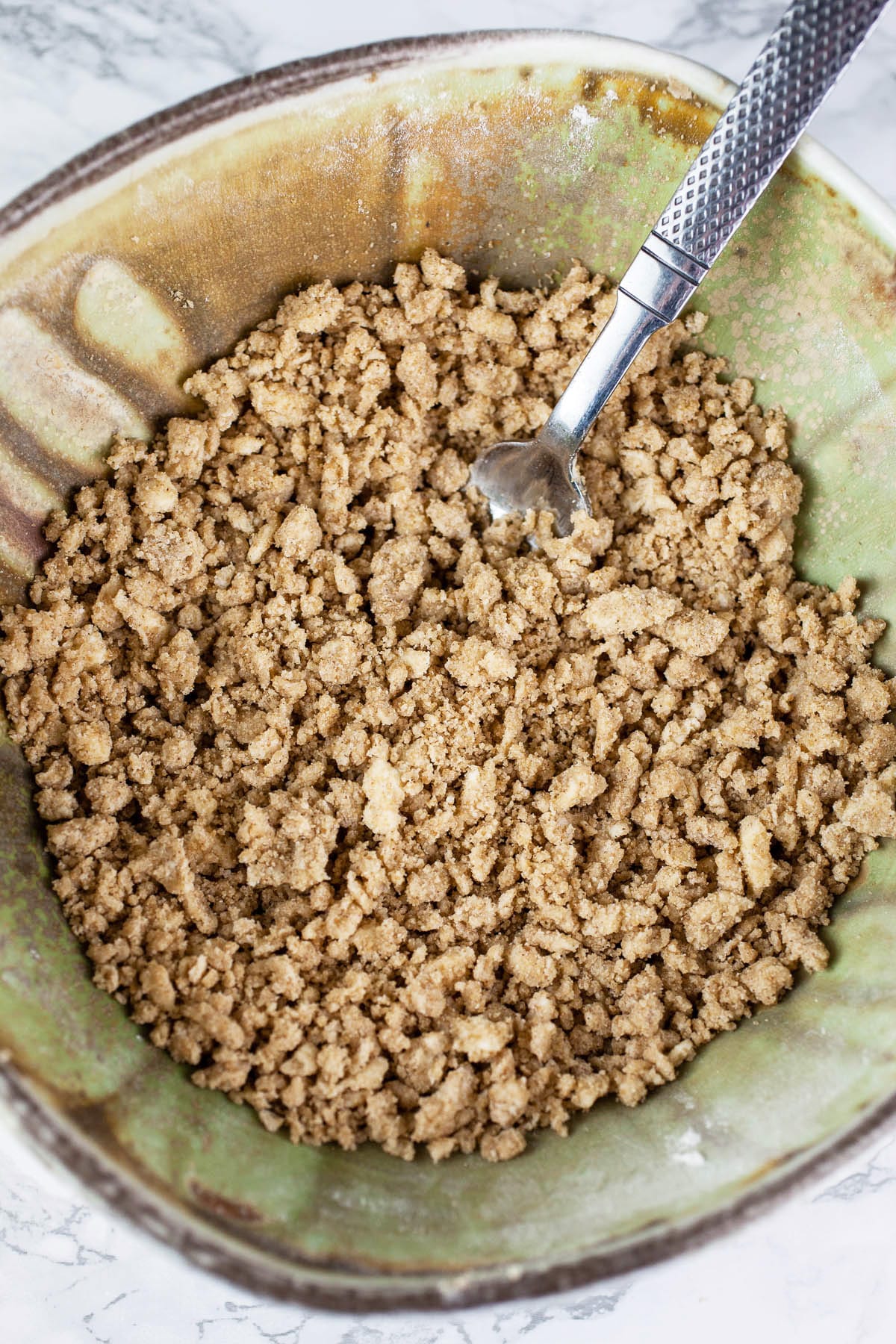 Streusel topping in green ceramic bowl with spoon.