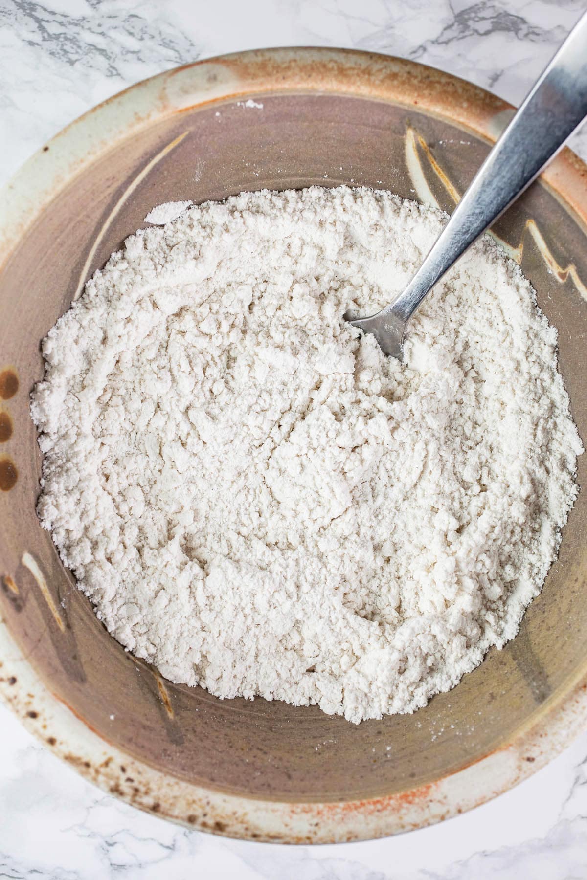 Dry ingredients in ceramic bowl with fork.