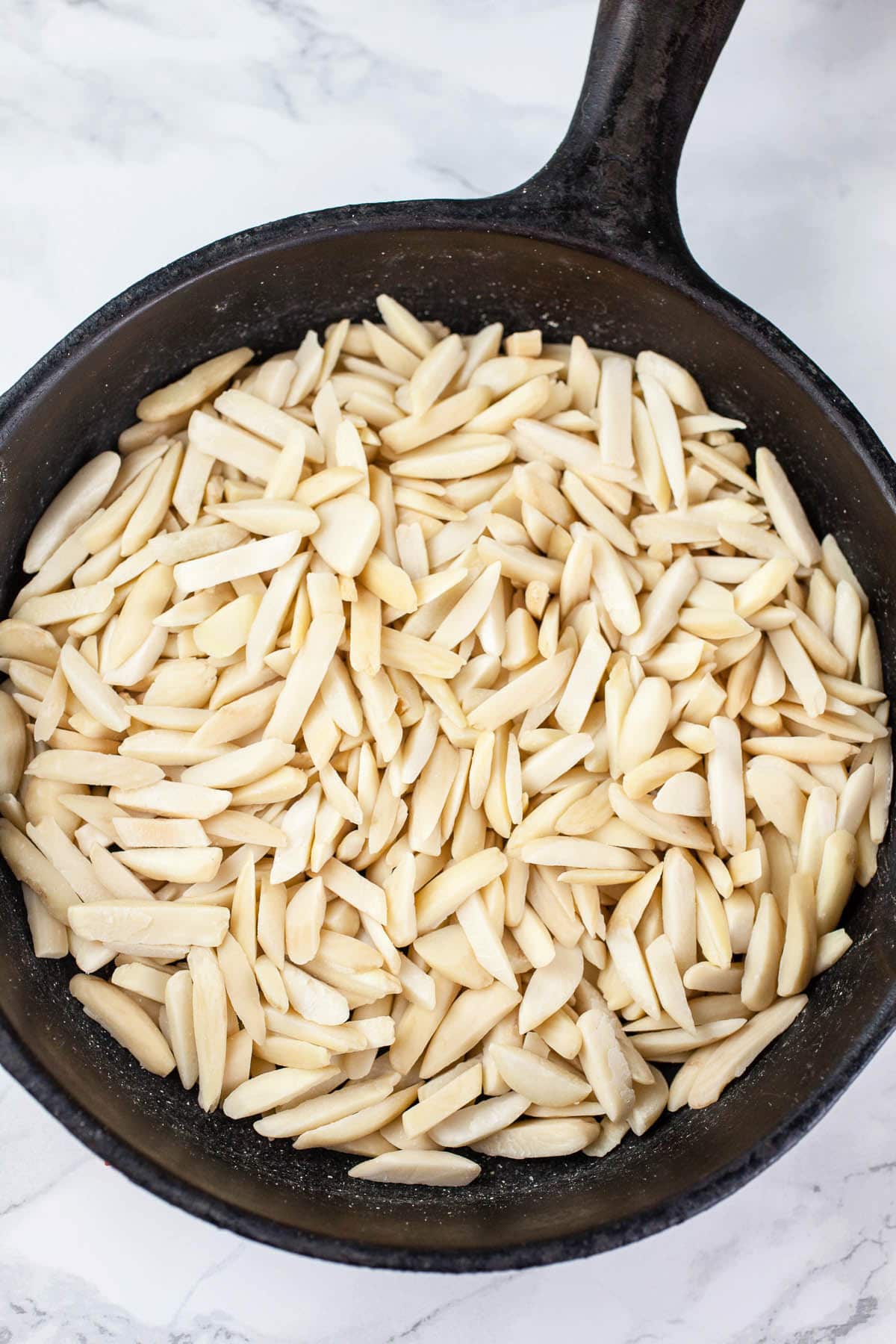 Sliced almonds toasted in small cast iron skillet.