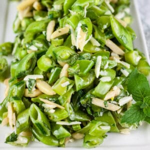 Healthy pea mint salad with almonds on white platter.