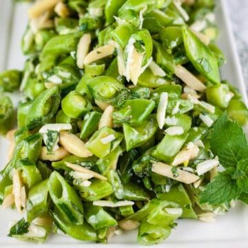 Healthy pea mint salad with almonds on white platter.
