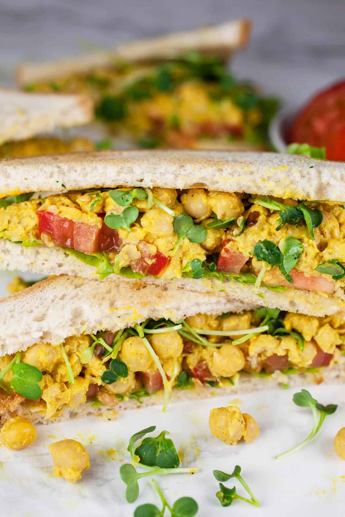 Curried chickpea salad sandwich cut into halves and stacked on itself.