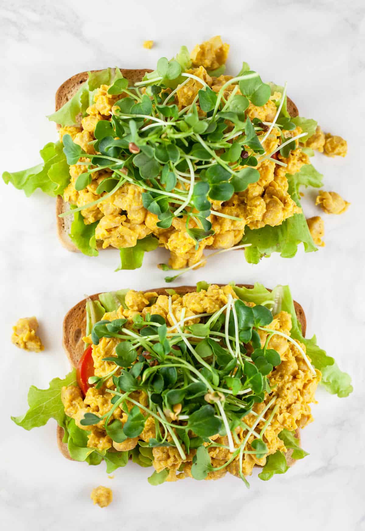 Microgreens, curried chickpeas, tomatoes, and lettuce on toasted bread.