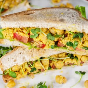 Curried chickpea salad sandwich halves cut and stacked on itself.