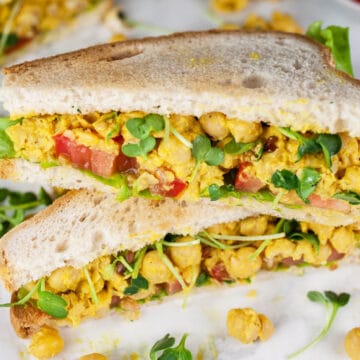 Curried chickpea salad sandwich halves cut and stacked on itself.