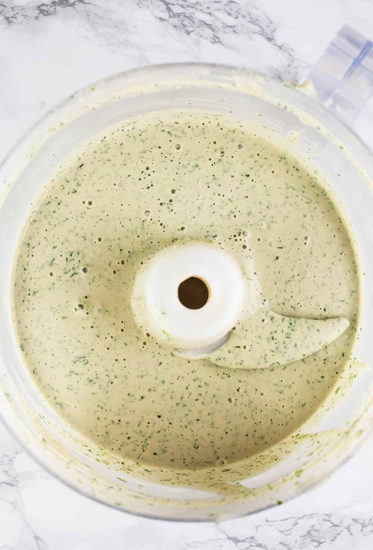 Herb tahini sauce in food processor.