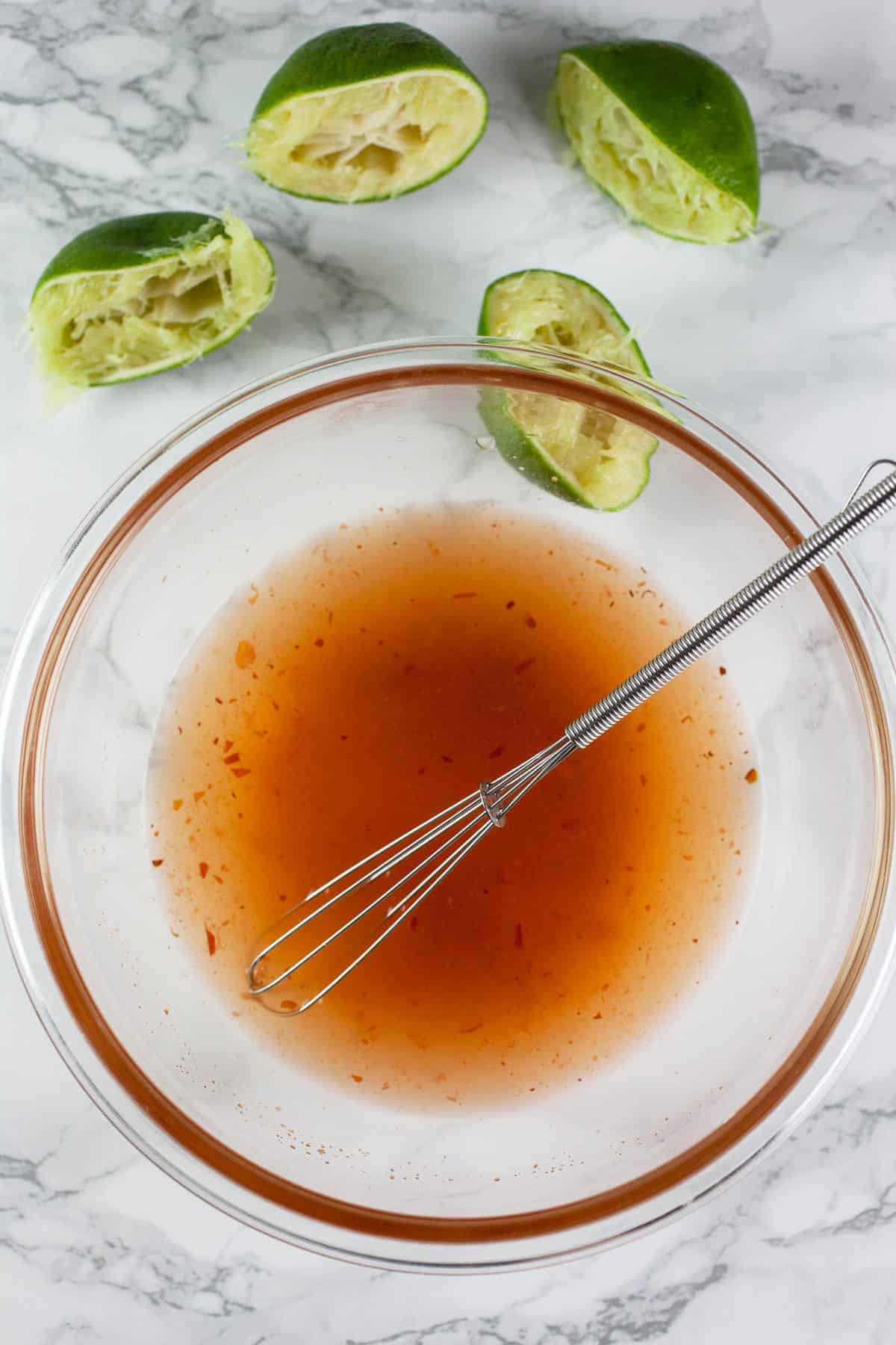 Chili lime salad dressing in small glass bowl with whisk.