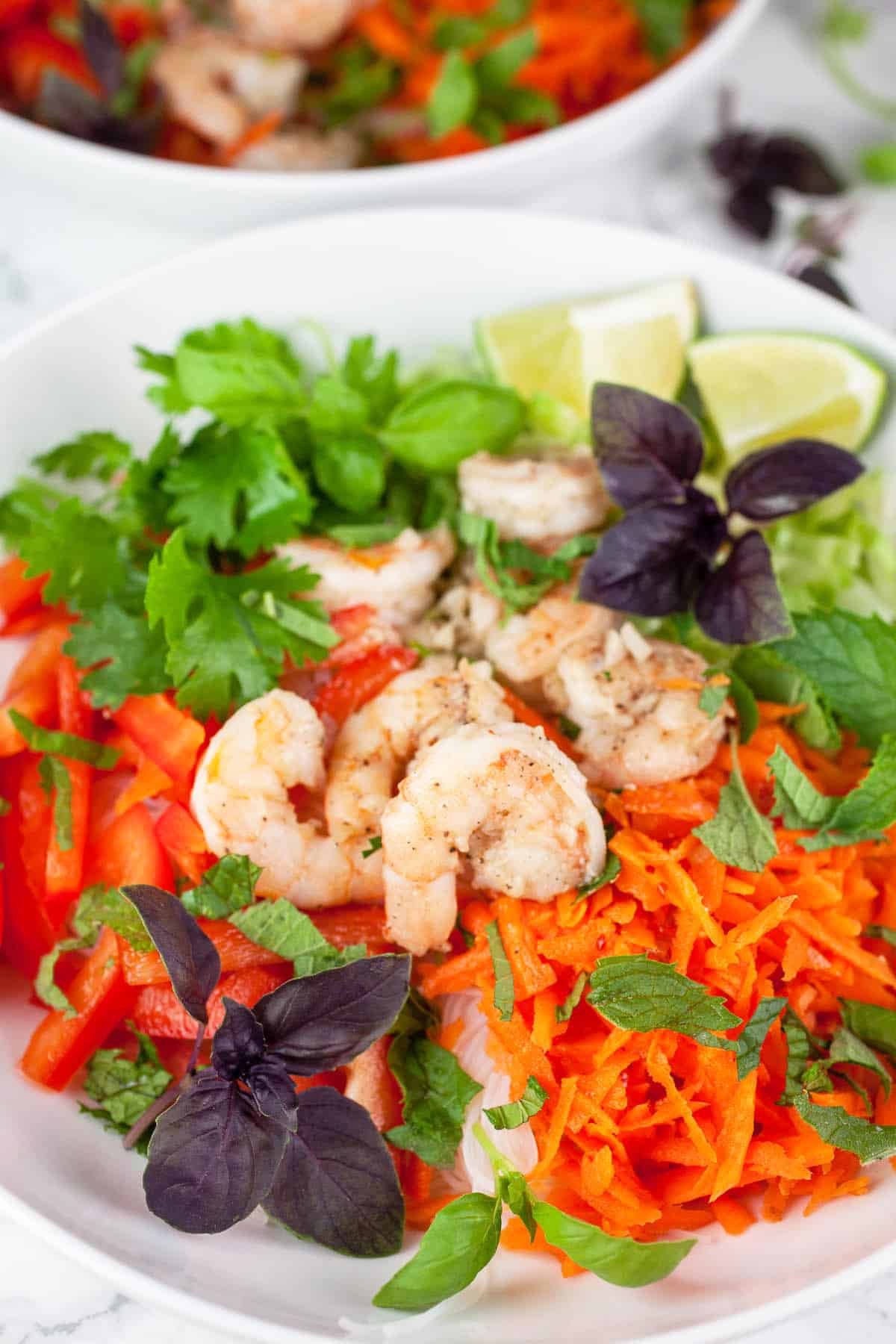 Vietnamese salad with shrimp, veggies, and herbs in white bowls.