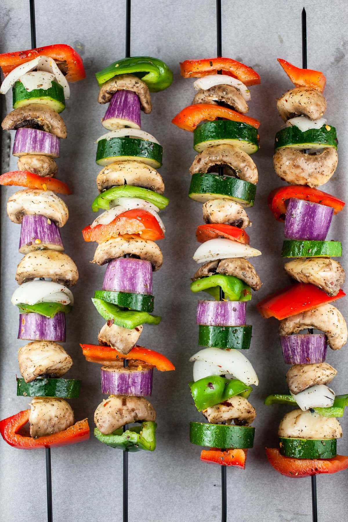 Uncooked vegetables on metal skewers.