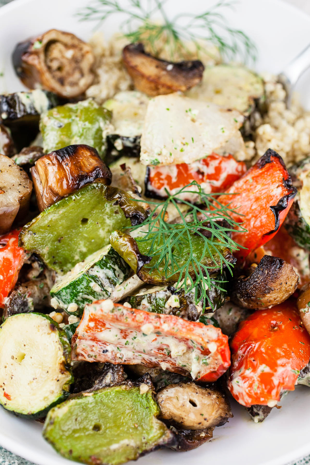 Summer roasted vegetable salad with herb tahini in white bowl.