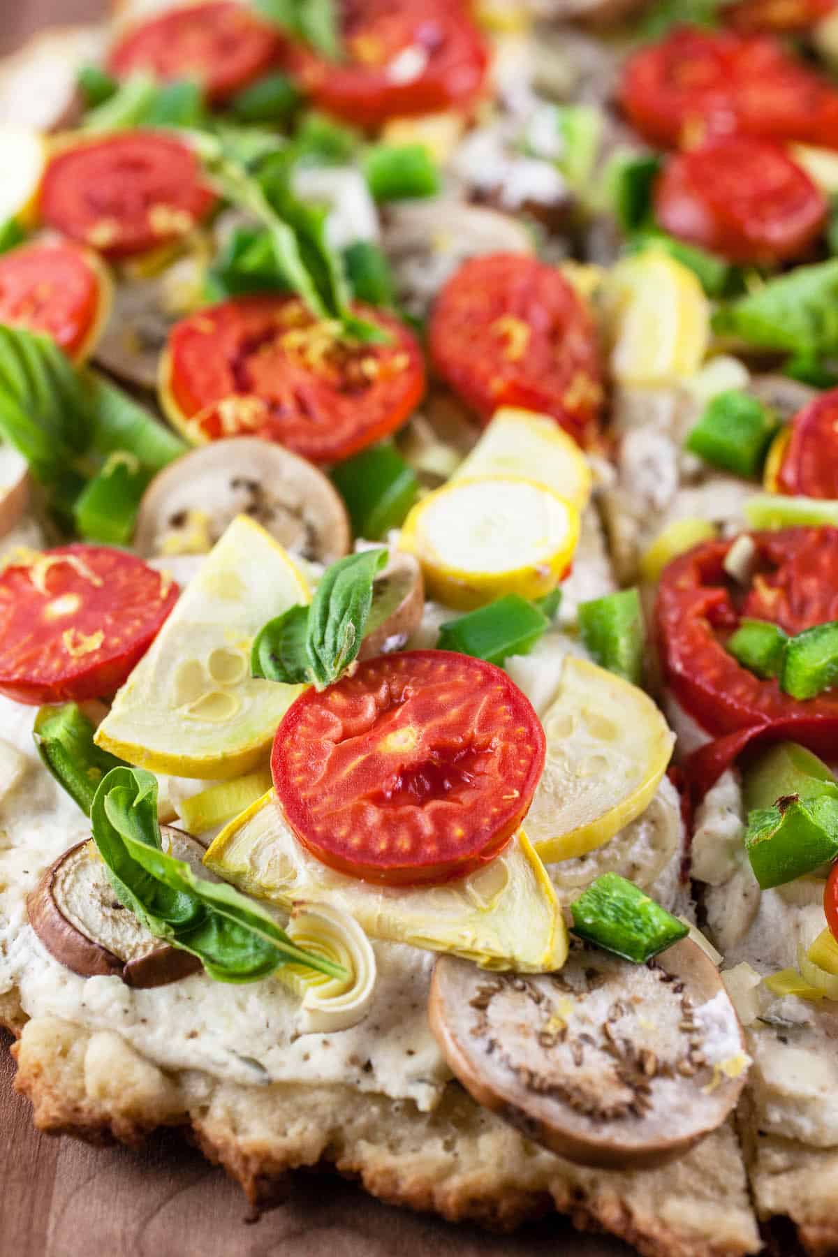 Farmers market pizza on wooden cutting board cut into piecces.