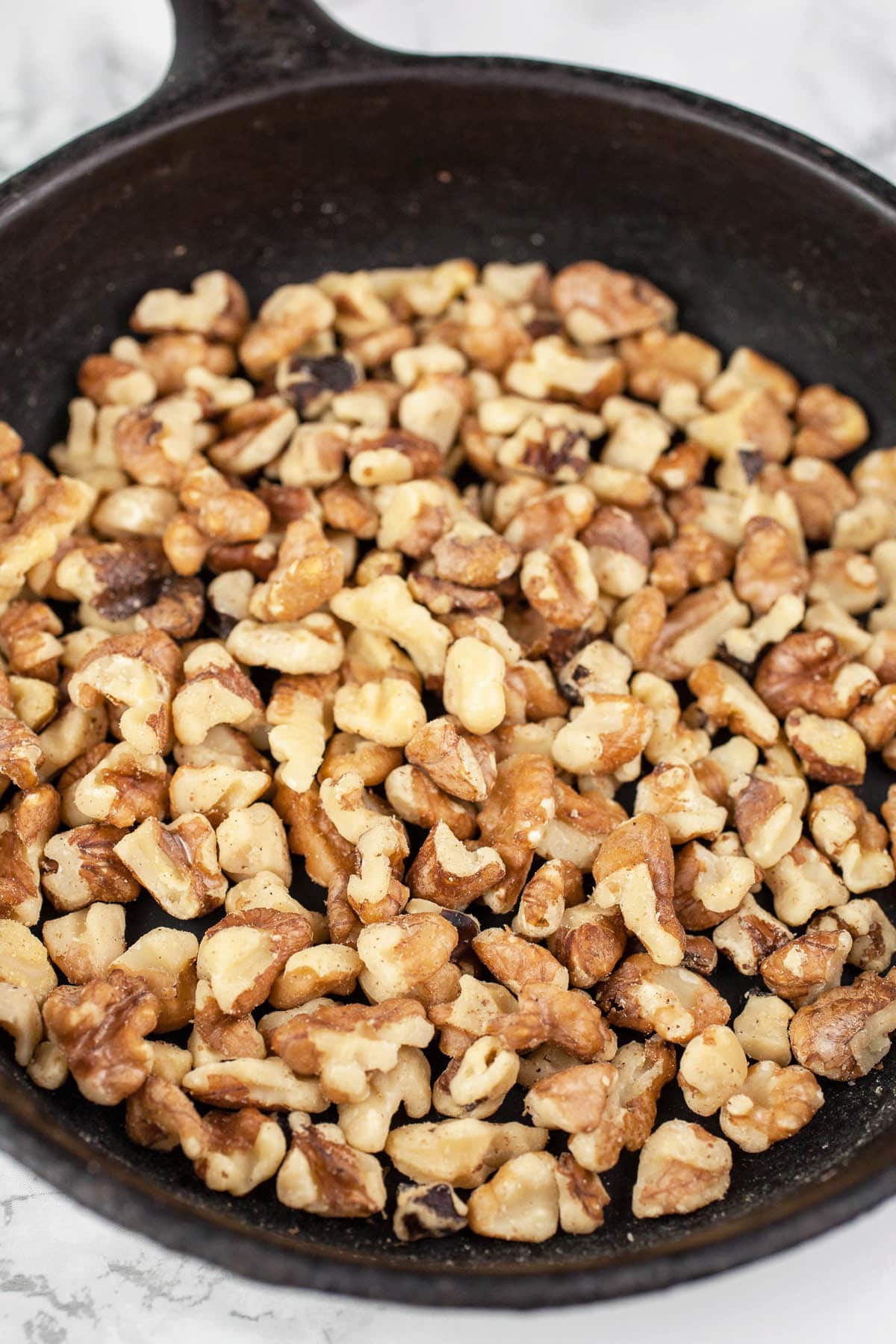 Toasted walnuts in small cast iron skillet.