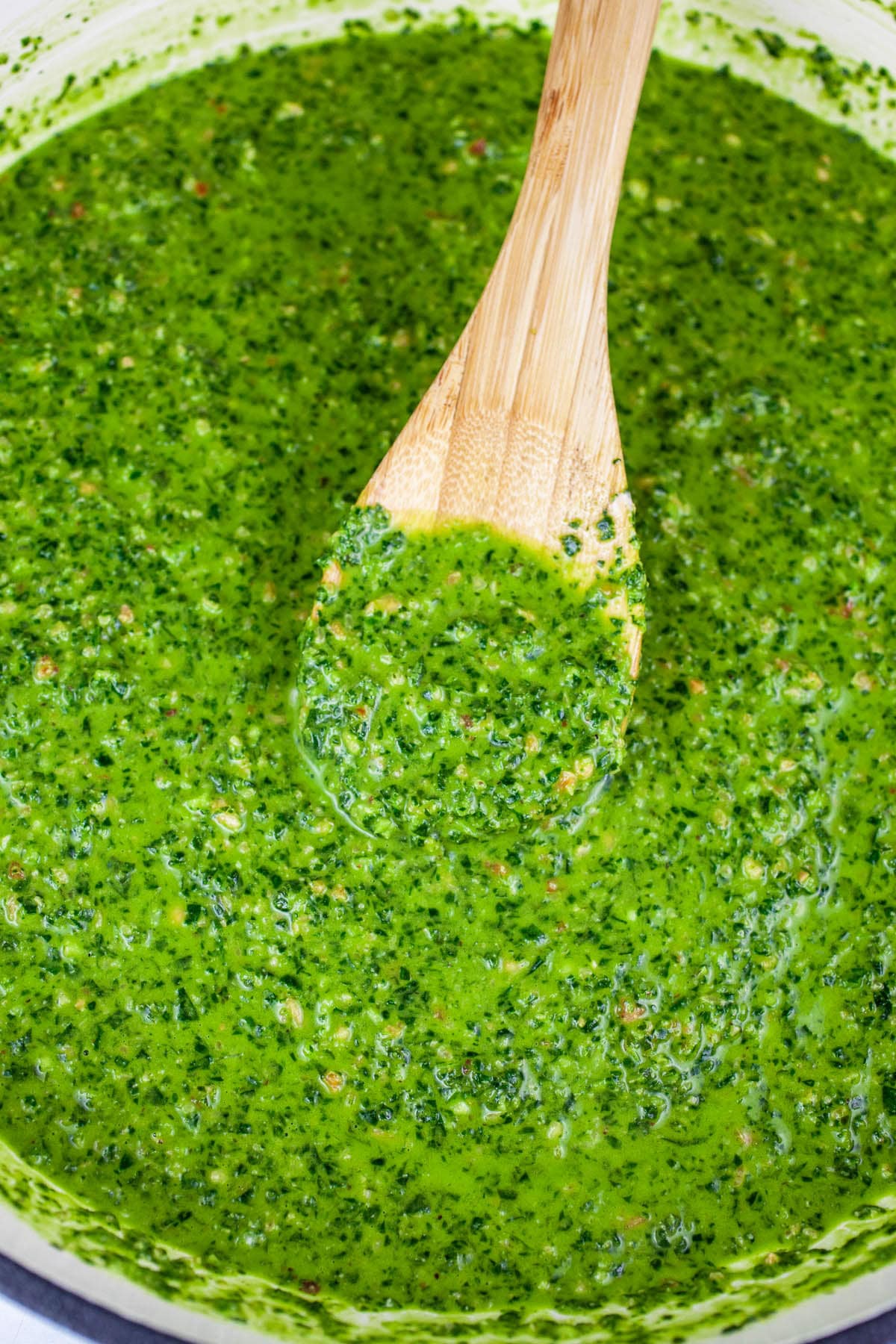 Pesto sauce in skillet with wooden spoon.