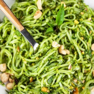 Rice noodles tossed in Thai basil pesto sauce with fork.