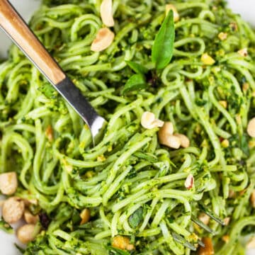 Rice noodles tossed in Thai basil pesto sauce with fork.