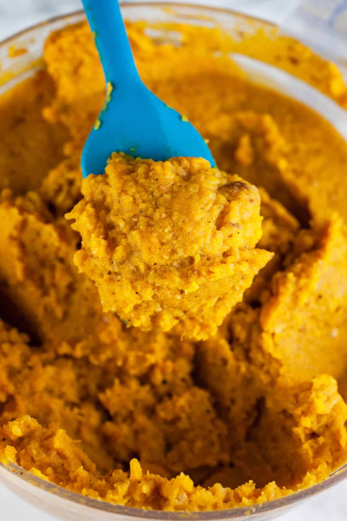 Squash bean dip on blue spatula lifted from food processor.