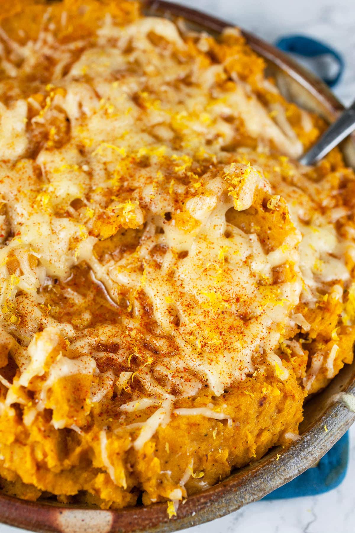 Baked butternut squash dip with melted cheese in ceramic pie plate.