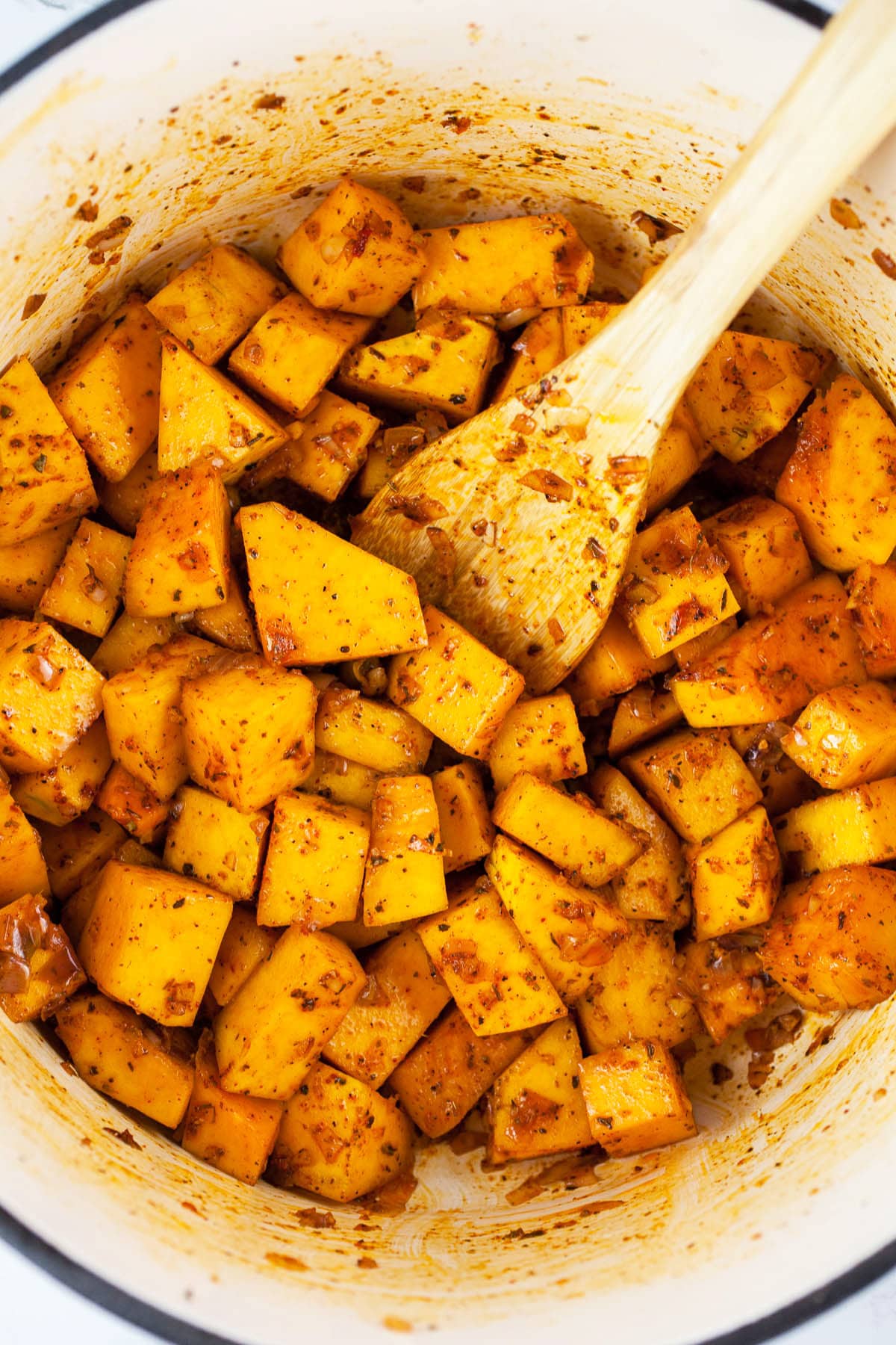 This Crockpot Butternut Squash and Sausage Soup is perfect for the cold winter months! It's hearty, healthy, and easy to make. This soup is made in the slow cooker. It's got chicken sausage, kale, and butternut squash. Soup is one of the best comfort foods out there! I love hearty soup recipes like this. #soup #crockpot #slowcooker #butternutsquash #sausage #kale Butternut squash chunks sautéed in Dutch oven with spices.