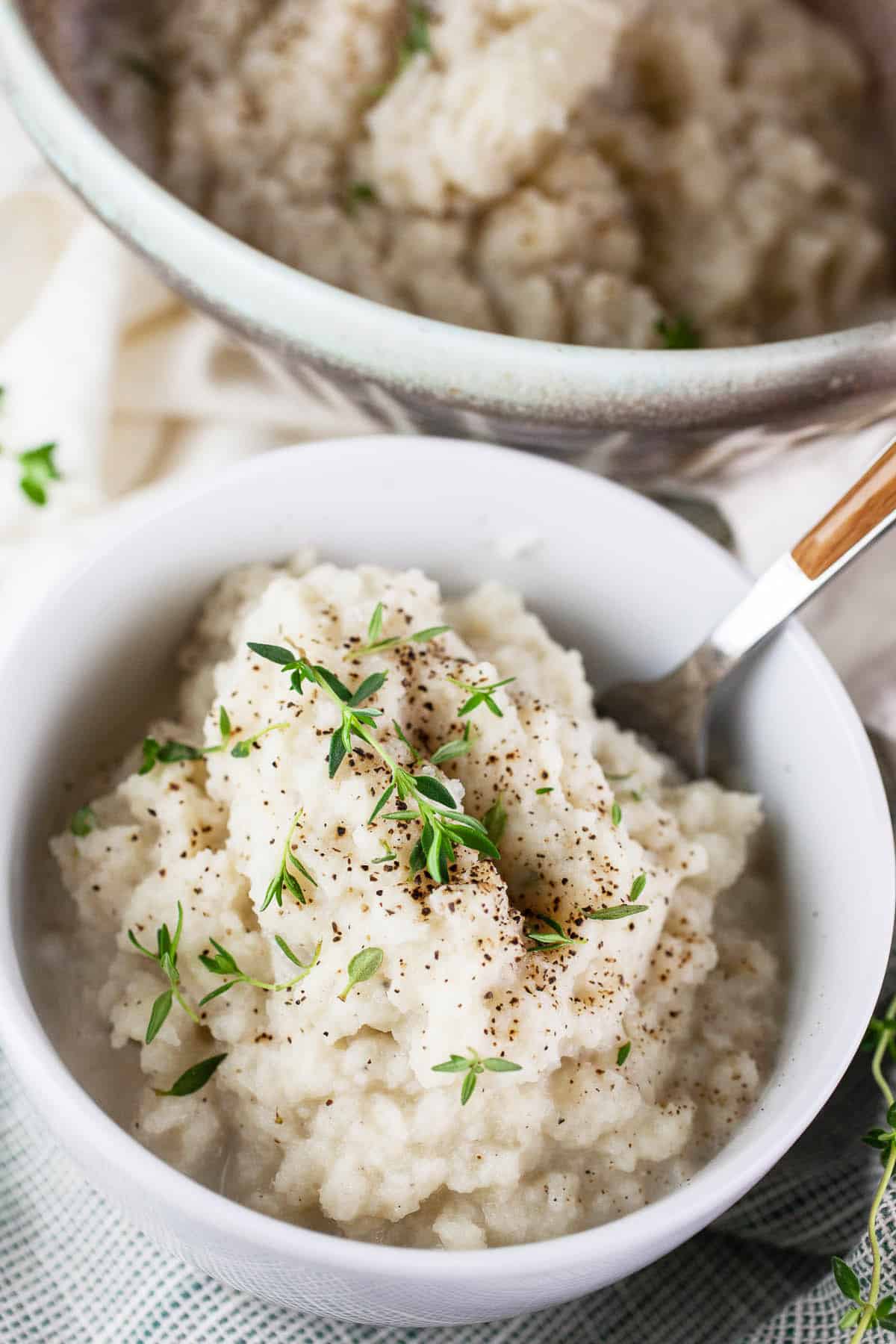 Kohlrabi mash with fork in white bowls.