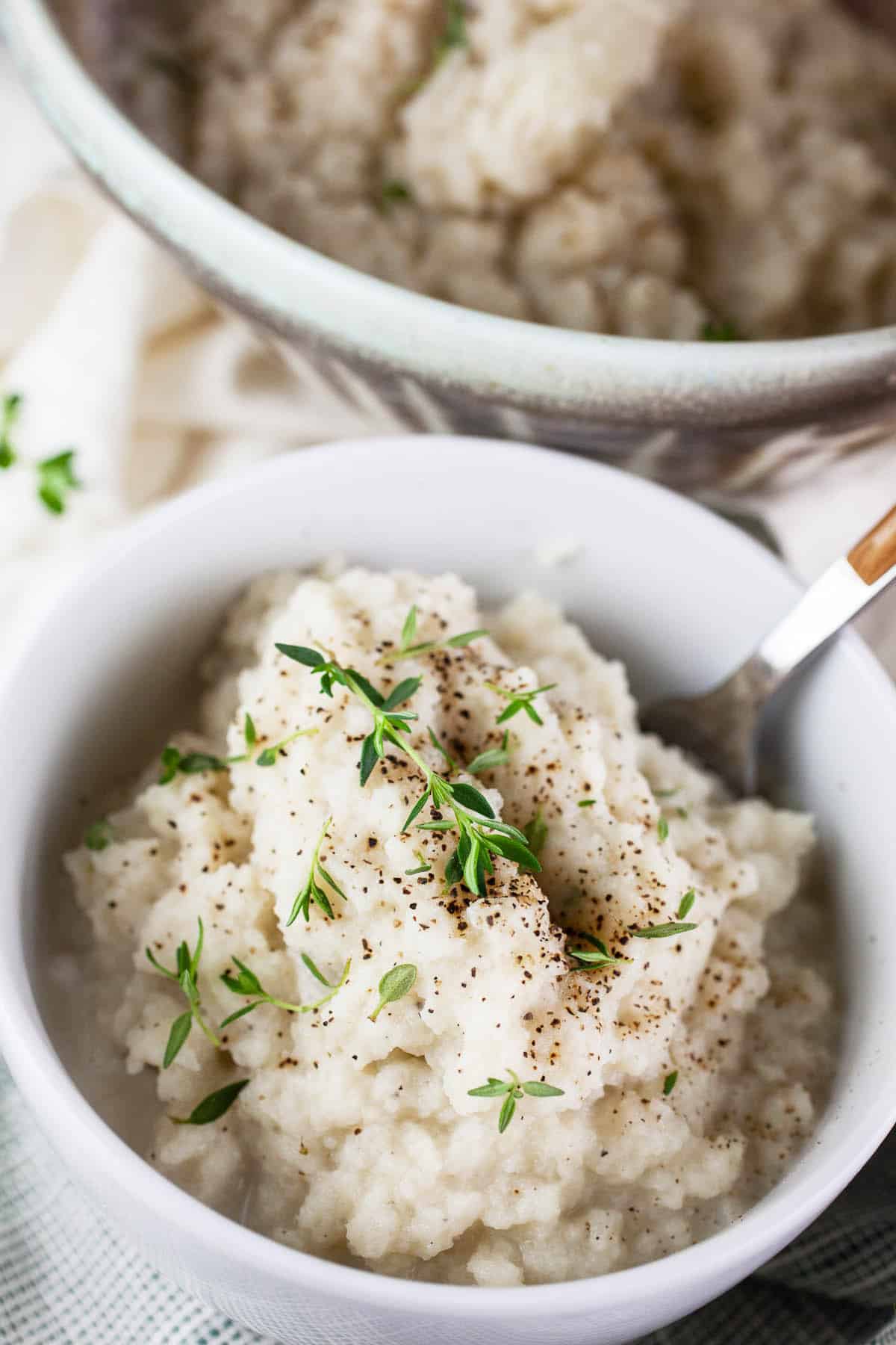 Mashed kohlrabi with fresh thyme in white bowls.