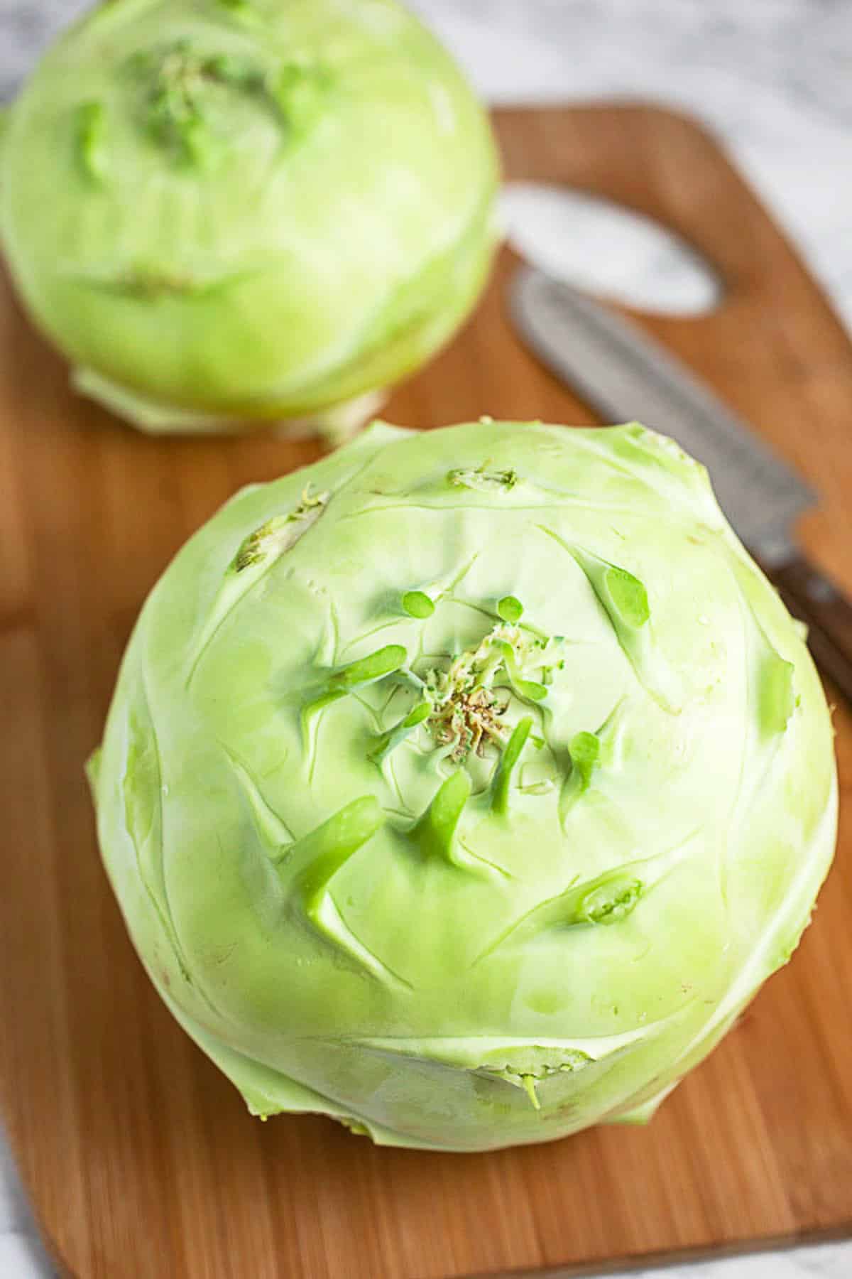 Kohlrabi with leaves removed on wooden cutting board.