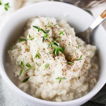 Mashed kohlrabi in small white bowl with fork.