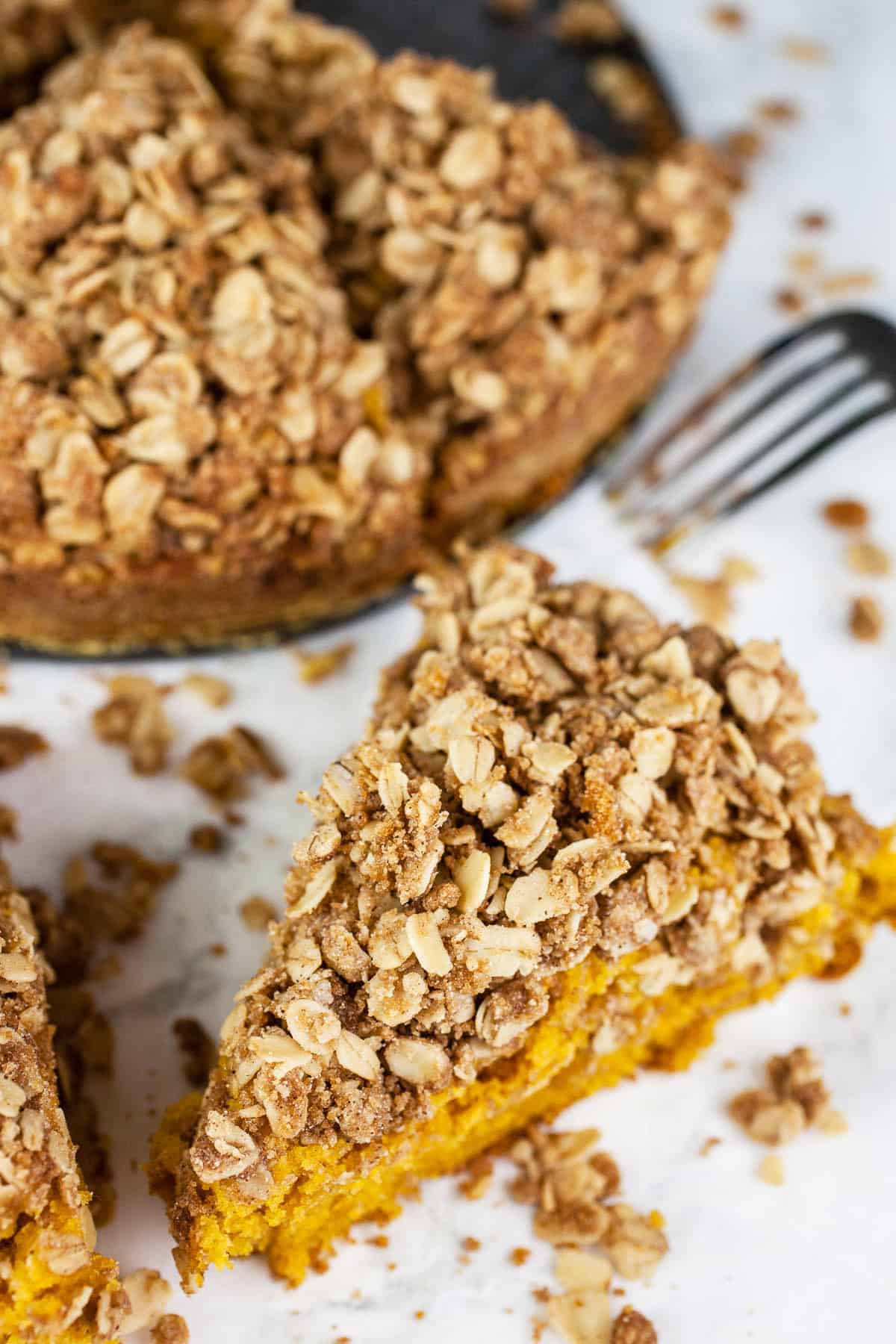 This Pumpkin Coffee Cake with Oatmeal Struesel Topping is the perfect fall breakfast or dessert! It's moist and fluffy, easy to make, and topped with a sweet cinnamon oatmeal streusel topping. This pumpkin coffee cake recipe is made from scratch and is great for Thanksgiving, the holidays, or all year round. Crumbly struesel is the best! So good with a cup of coffee! #ad #flahavans #oatspiration #pumpkin #coffeecake #oatmea Slice of pumpkin streusel coffee cake with fork.
