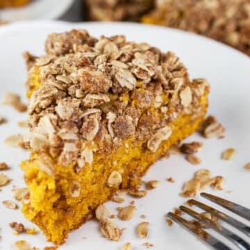 Slice of pumpkin streusel coffee cake on white plate with fork.