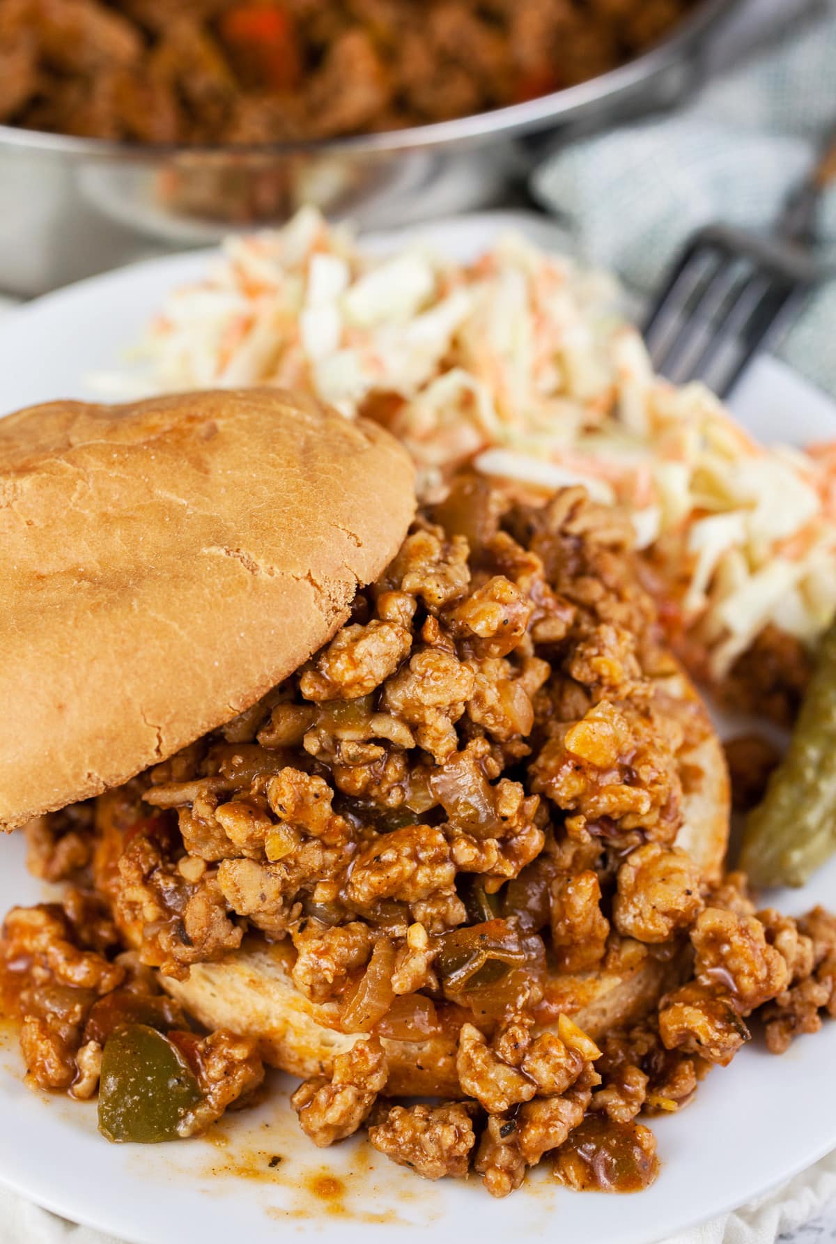 Ground chicken sloppy joes with coleslaw and pickle.