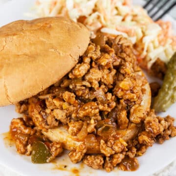 Ground chicken sloppy joes with coleslaw and pickle.