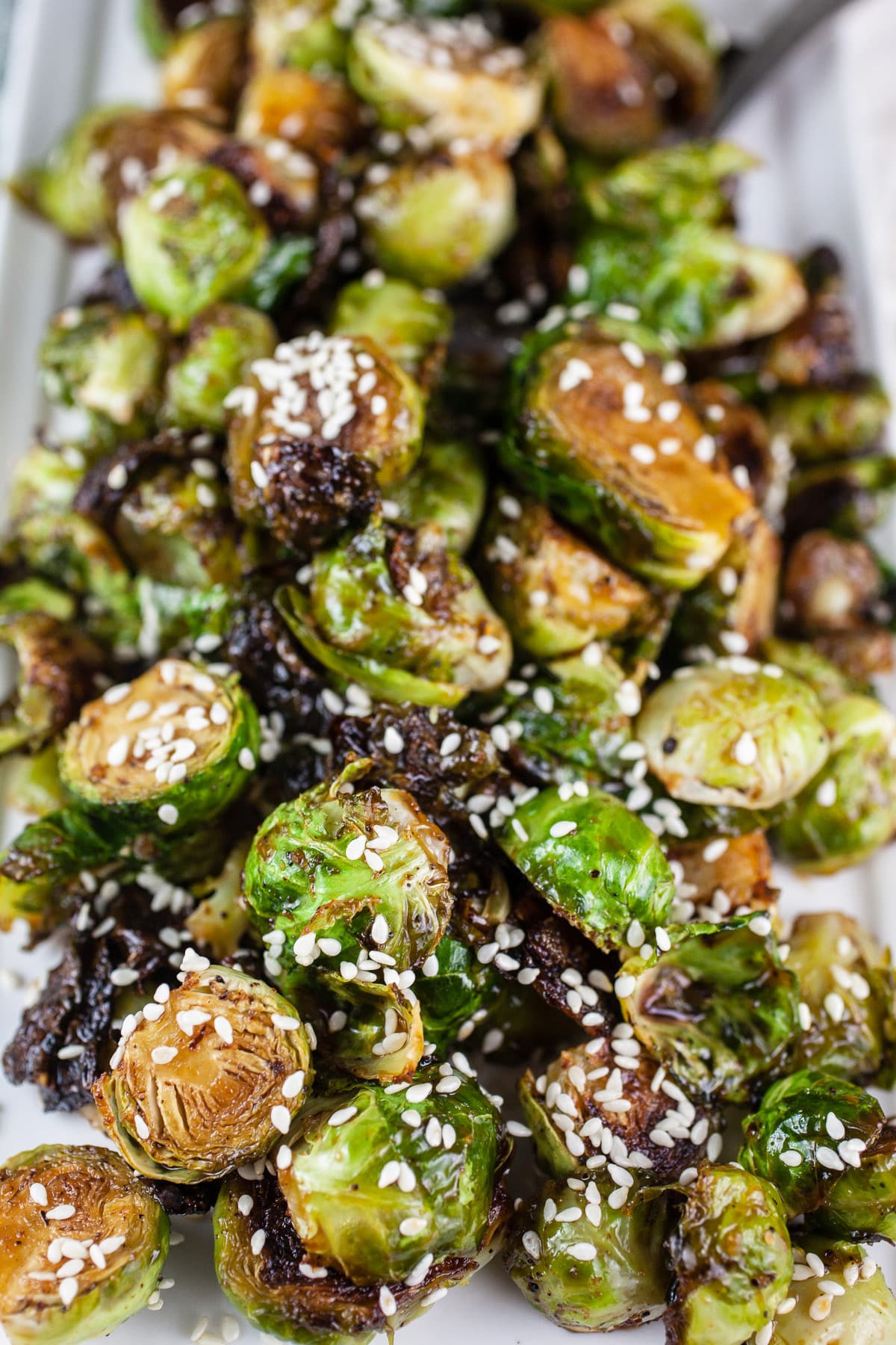 Maple roasted Brussels sprouts with sesame seeds on white platter.