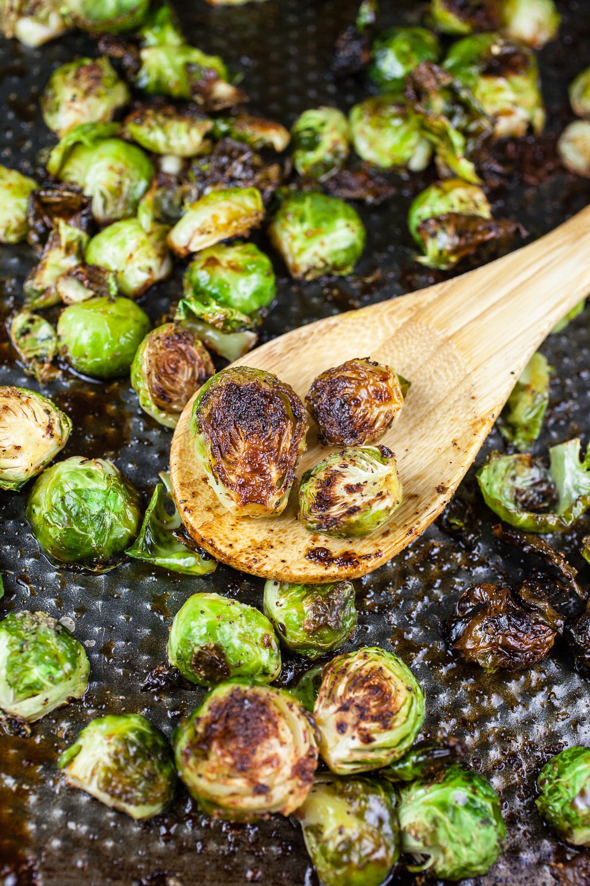 Roasted Brussels sprouts tossed in glaze on baking sheet.