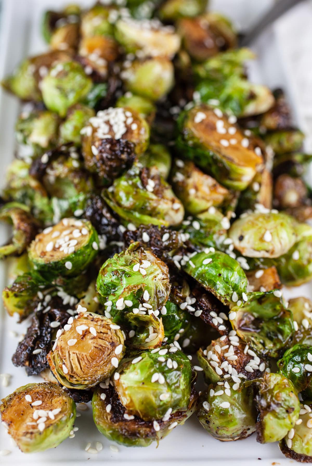 Roasted Brussels sprouts with sesame seeds on white platter.