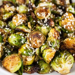 Maple sesame roasted Brussels sprouts in white bowl.